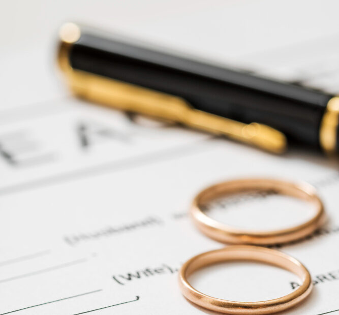 Two wedding rings and a pen placed on a legal document, symbolising marriage, divorce, or partner visa applications