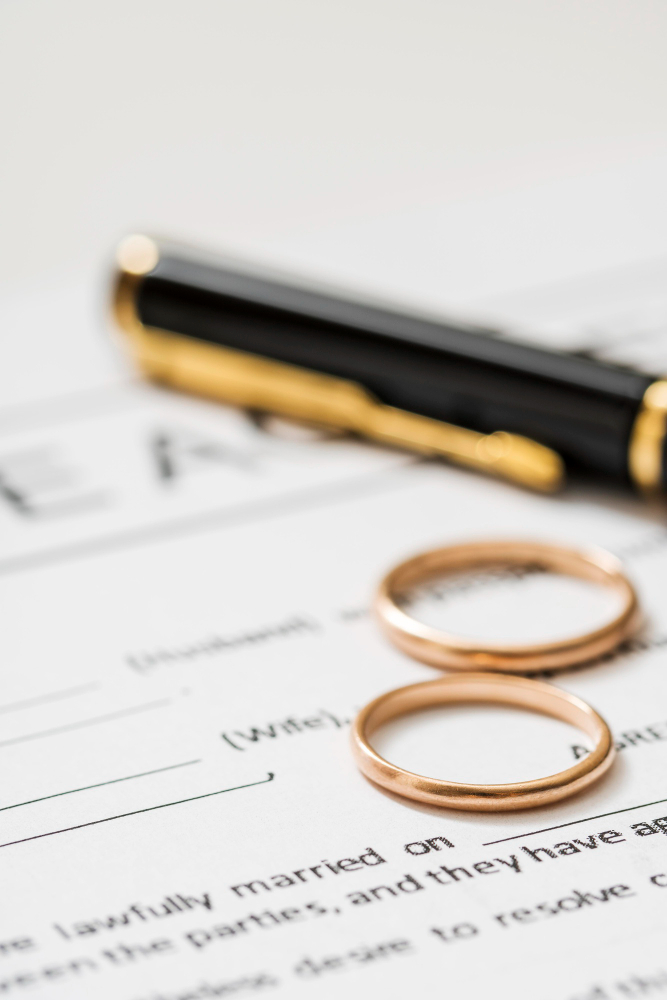 Two wedding rings and a pen placed on a legal document, symbolising marriage, divorce, or partner visa applications
