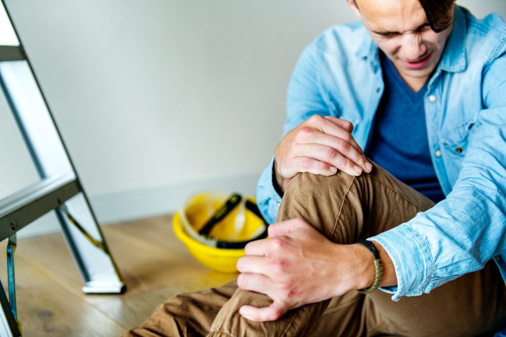 A man with an injured leg at work, representing a workplace accident and potential compensation or legal support needs.