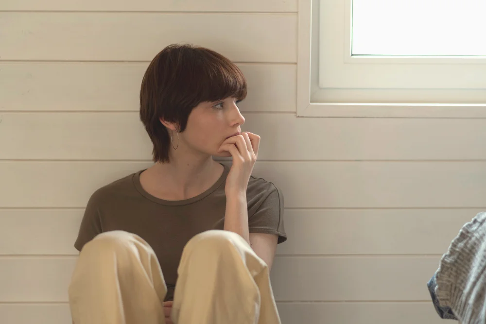 Worried employee sitting alone by a window, representing redundancy, job loss, and employment termination in the UK.