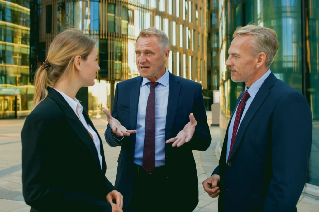 Business professionals discussing commercial and franchise disputes outside a corporate office building, representing legal negotiation and conflict resolution in the UK.