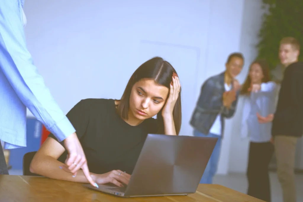 A stressed employee sitting at her desk while being confronted at work, representing unfair dismissal and workplace discrimination claims.