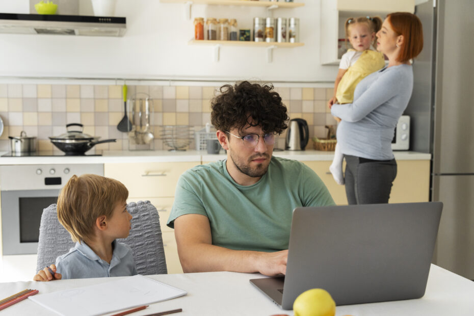 Family gathered at the kitchen dad is working on his laptop