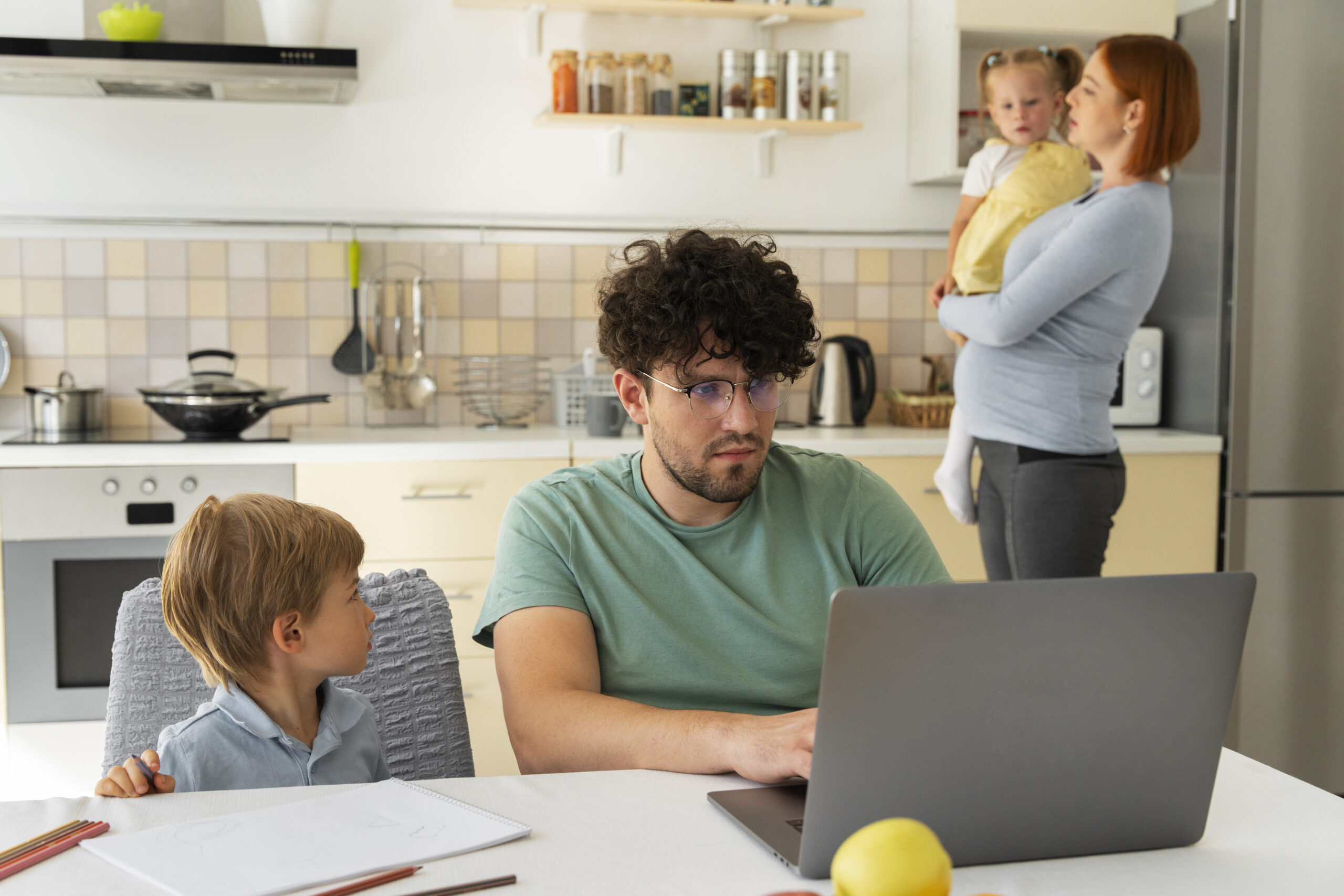 Family gathered at the kitchen dad is working on his laptop